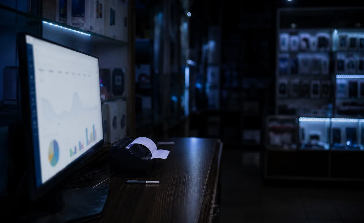 A sales and profit report on the shop's monitor after closing, a printed receipt and pen on the counter.